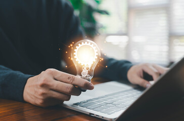 A glowing light bulb with gear icons held above a laptop represents innovation, creative thinking, digital solutions, and modern technology concepts for business development and startup ideas.