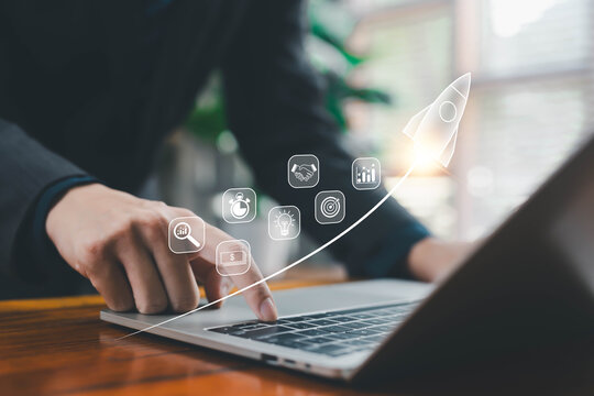 A glowing rocket icon rising above a laptop with business and analytics symbols represents startup growth, digital innovation, financial progress, and strategic development for modern companies.