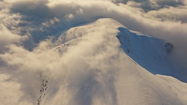 Misty glow casting shadows on icy mountain summit amidst drifting snow, Overcast brightness enveloping wintry peak with swirling snow flows and hazy illumination