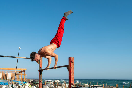 Man performing handstand on parallel bars calisthenics workout - Powered by Adobe