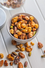 Nuts coated in sugar glaze in bowl  on white table.