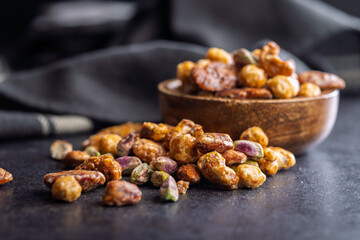 Nuts coated in sugar glaze on black table.