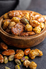 Nuts coated in sugar glaze in bowl on black table.