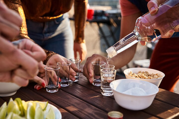 Friends enjoying a lively rooftop celebration with drinks and laughter under the sunset