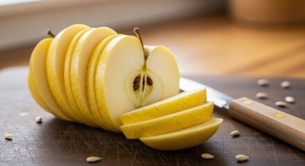 Close-up of a yellow fruit, possibly a quince or apple, expertly sliced into thin pieces on a dark cutting board with a knife.