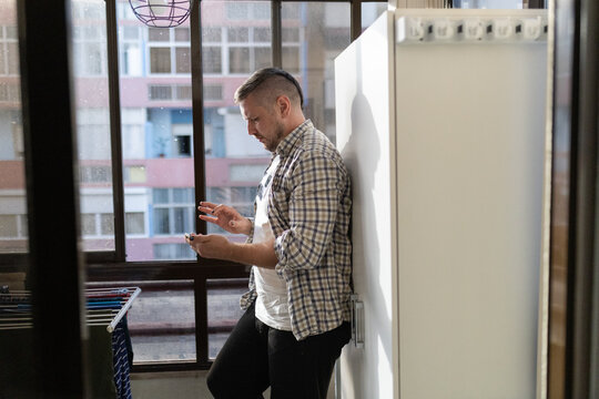 Young man using mobile phone leaning on wall