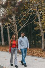 Fototapeta premium partners enjoy leisurely walk amidst autumn foliage, youthful duo leisurely wandering in city park setting