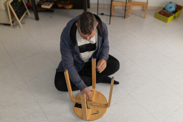 Person assembling wooden stool in living room