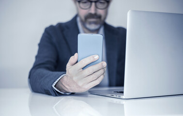 Mobile Communication: A Modern Professional Engaged with a Smartphone While Working on a Laptop