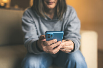 A Relaxed Person on a Sofa Using a Blue Smartphone while Enjoying Cozy and Warm Ambient Light