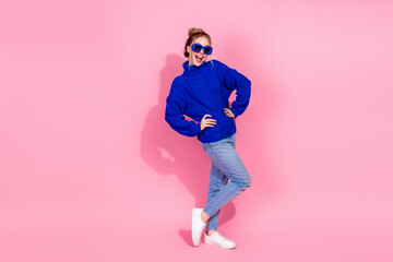 Young woman in blue knit sweater posing happily against pink background for lifestyle fashion and...