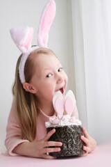 A little girl holds a creative Easter cake with bunny ears, a concept for a happy Easter holiday
