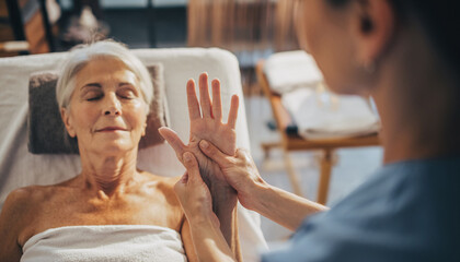 Senior woman enjoying a relaxing hand massage at a spa. Illustrates wellness, selfcare, and therapeutic touch. Ideal for health, beauty, and lifestyle content.