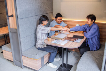 Dynamic team celebrating project win with hands together in modern office pod