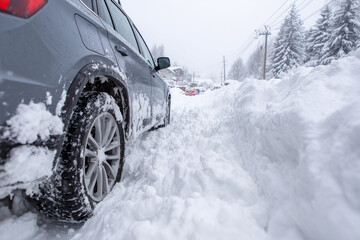 Car trapped deeply in snow after severe winter storm with wheels buried in icy conditions