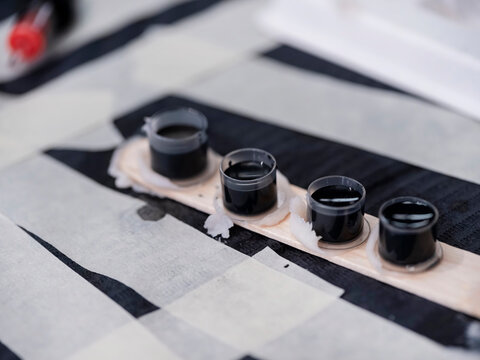 Row of black tattoo ink caps arranged on striped surface with supplies