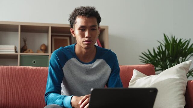 Asian teenage man learning sign language via internet with technology on tablet at home