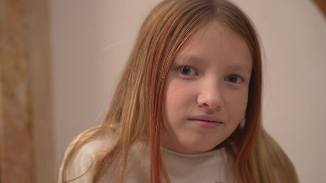 Close-up of the face of a beautiful little girl with long blonde hair. A cute girl smiles modestly