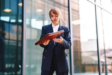 Businesswoman reviews documents outside a modern office building during the afternoon