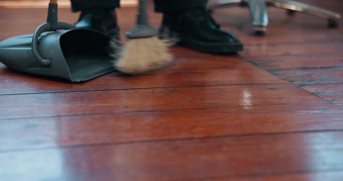 Feet, broom and sweeping floor at barbershop with hair care, hygiene and trimmings at small business. Person, shoes and cleaning with tools for dirt, grooming and services with dustpan at salon
