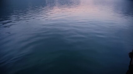 Calm, serene water surface at dusk with gentle ripples and soft lighting, creating a tranquil and relaxing mood.