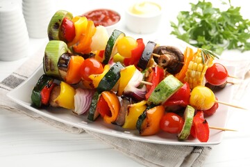 Skewers with tasty grilled vegetables, sauces and parsley on white wooden table, closeup