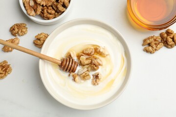 Delicious Greek yogurt with honey and nuts on white table, flat lay
