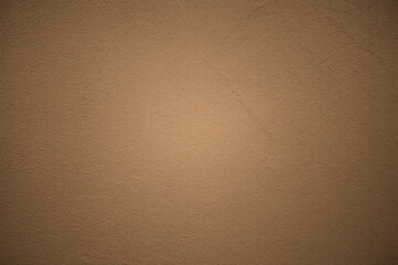 A close up shot of a tan textured wall with subtle variations in color and lighting across the surface