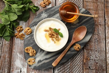 Delicious Greek yogurt with honey, nuts and mint on wooden table, flat lay