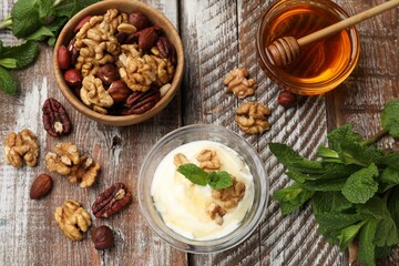 Delicious Greek yogurt with honey, nuts and mint on wooden table, flat lay