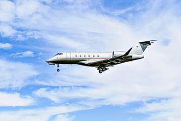 Private business plane flying under blue sky with white clouds	