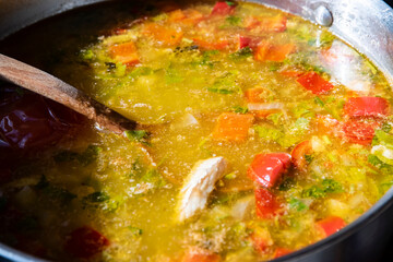 Hearty homemade fish soup with vegetables simmering in a pot, captured close-up in warm natural light