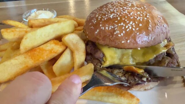 Eating a cheeseburger with French fries