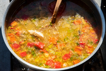 Hearty homemade fish soup with vegetables simmering in a pot, captured close-up in warm natural light