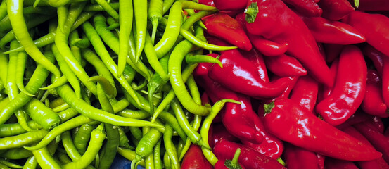Fresh green chili peppers and large red peppers piled on Turkish market stall, vibrant rustic harvest scene ideal for culinary, lifestyle, and authentic cultural projects