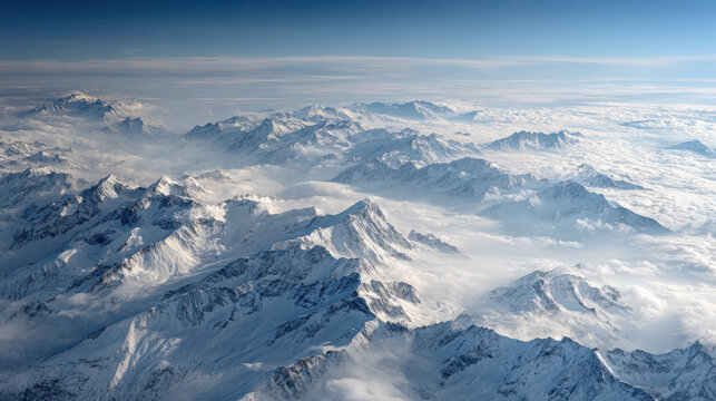 Aerial view of snow-capped mountains and clouds under a clear blue sky. This stunning aerial view captures the majestic beauty of snow-covered mountain peaks rising above the clouds