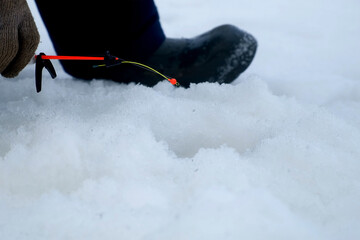 Ice fishing in action fisherman catching fish pulls fishing rod out of cold water. Fishing...