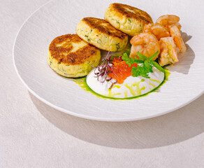 Crispy cottage cheese pancakes with shrimp served on a white plate with colorful garnish