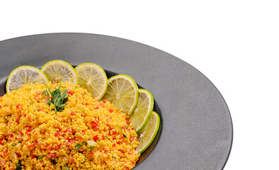 Colorful couscous salad served with fresh lime slices on a dark plate