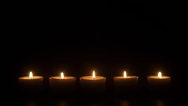 Burning tea light candles glowing brightly in a dark room at varying arrangements, creating a tranquil atmosphere