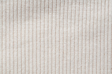 Close-up of a cream-colored ribbed knit fabric texture for backgrounds and design