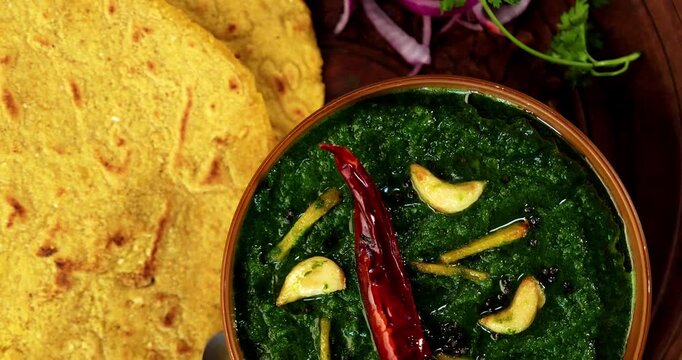 Makki Ki Roti & Sarson Ka Sag is basically Corn floor flat bread & curry using mustard greens respectively. Popular Punjabi food. Served in a bowl and plate over moody background. selective focus