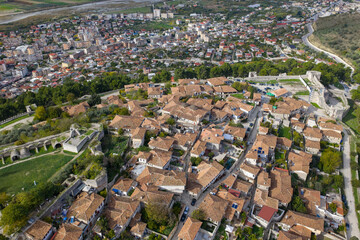 Aerial view of Berat Castle&rsquo;s hilltop neighborhood, showcasing tiled-roof homes and its fortified walls above the city below.