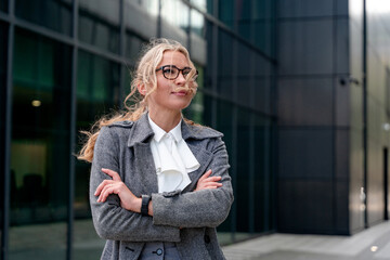 Fototapeta premium Business woman poses confidently outside modern office building in city