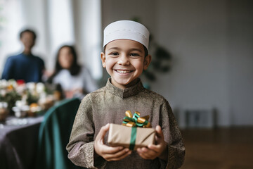 Joyful boy in traditional attire holding gift during celebration at home