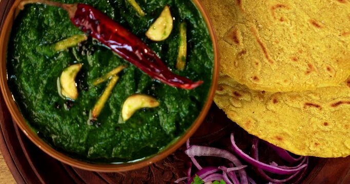 Makki Ki Roti & Sarson Ka Sag is basically Corn floor flat bread & curry using mustard greens respectively. Popular Punjabi food. Served in a bowl and plate over moody background. selective focus
