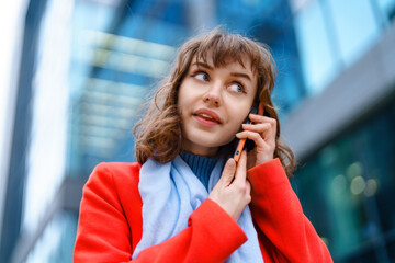 Young woman talking on the phone in a modern city setting during a sunny day