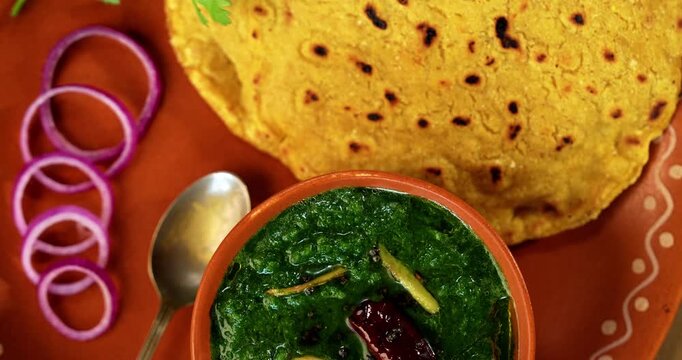 Makki Ki Roti & Sarson Ka Sag is basically Corn floor flat bread & curry using mustard greens respectively. Popular Punjabi food. Served in a bowl and plate over moody background. selective focus