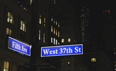 Paisaje urbano nocturno de Nueva York, EE. UU. Cartel indicador del cruce de la 5th Ave. con West 37th St iluminado en la noche.