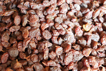 Fresh dried raisins close up filling frame with glossy, brown, and reddish tones